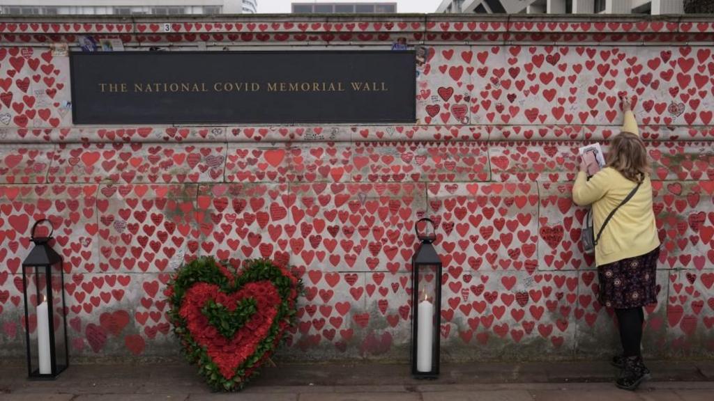 A woman adds a name to the National Covid Memorial Wall in London
