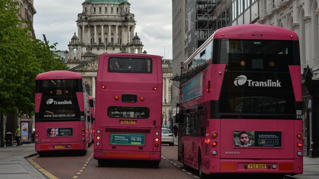 Three buses, each with the Translink logo on a main street in Belfast