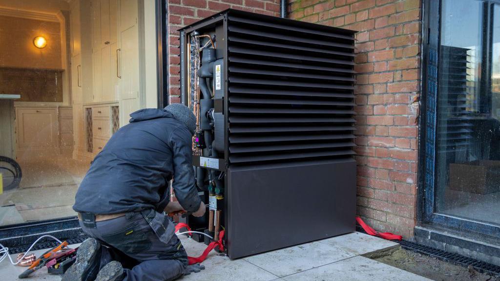 Air source heat pump installers install a heat pump unit into a house near Ashford, UK, on 29 November 2024 