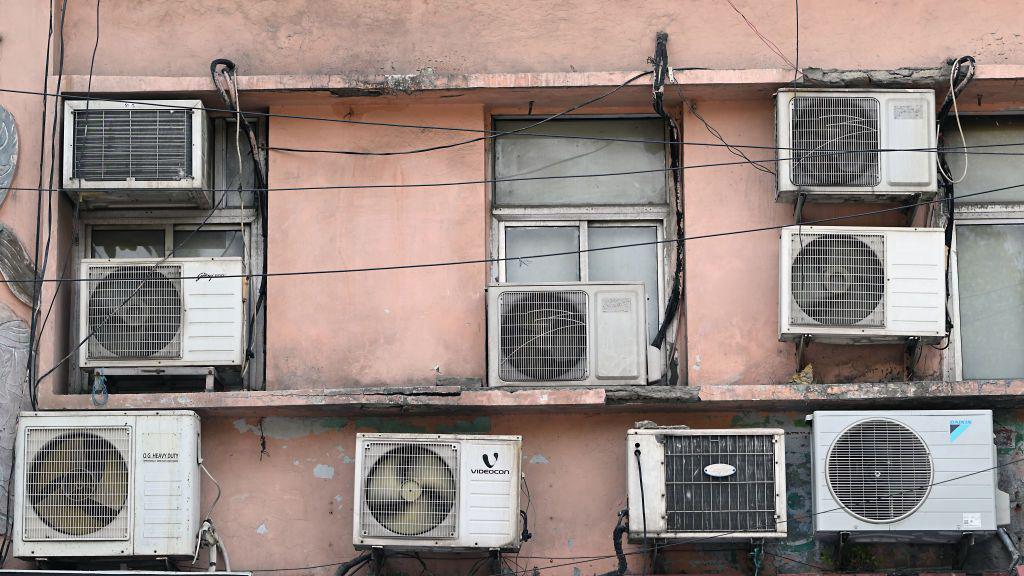 Air conditioning units hang from a building during high temperatures in New Delhi, India, on Thursday, May 30, 2024. T