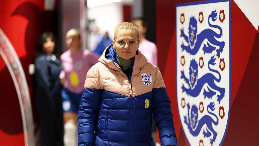 Sarina Wiegman next to an England badge 