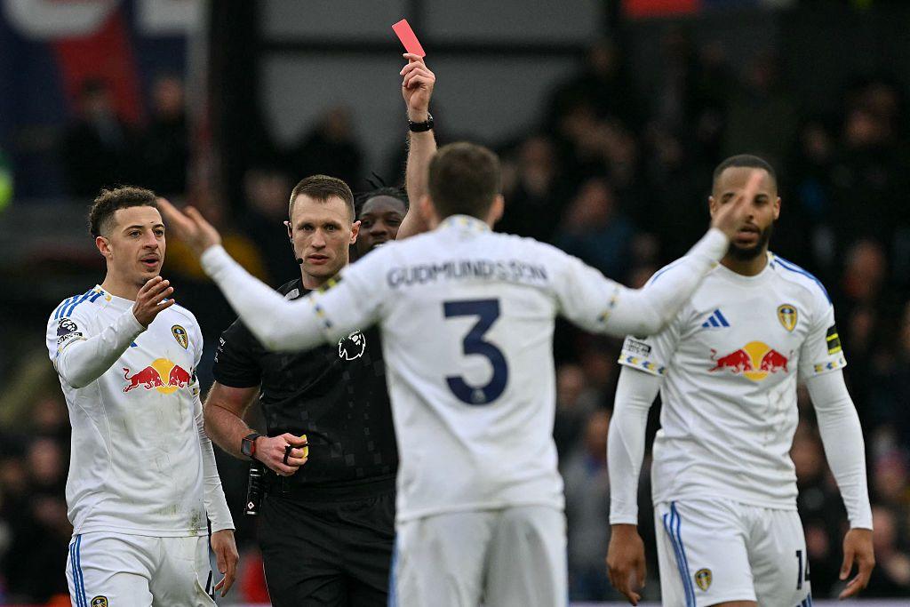 Thomas Bramall shows a red card to Leeds United's Gabriel Gudmundsson after appearing to forget he had already shown a yellow earlier in the game