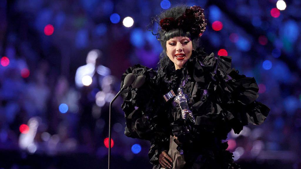 Lady Gaga giving a speech on stage after winning an award.