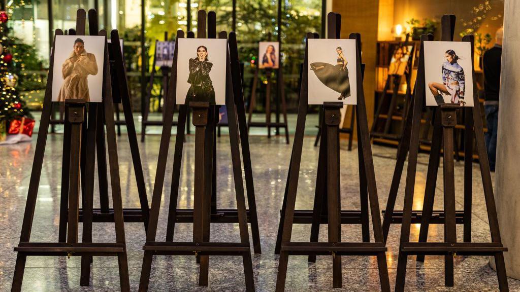 Four of Liz Hatton's photographs of women stand on easels.