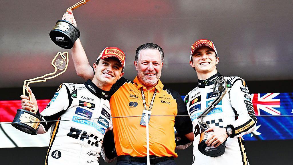 Race winner Lando Norris, McLaren CEO Zak Brown and third-placed Oscar Piastri stand on the podium un Monaco last year 