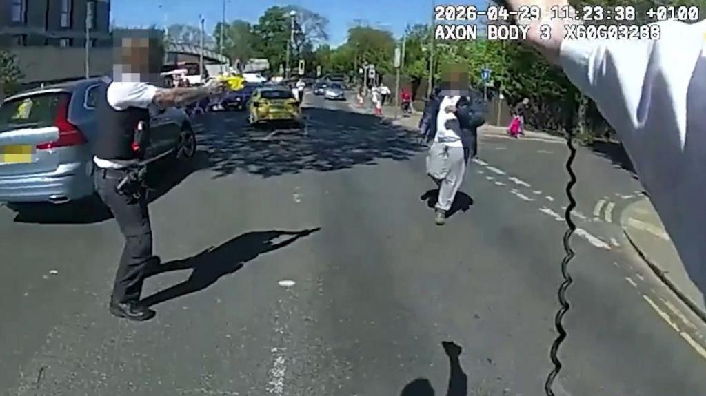 Body-worn footage showing a police officer's arm holding a Taser, another officer to the left and the knife suspect walking towards them