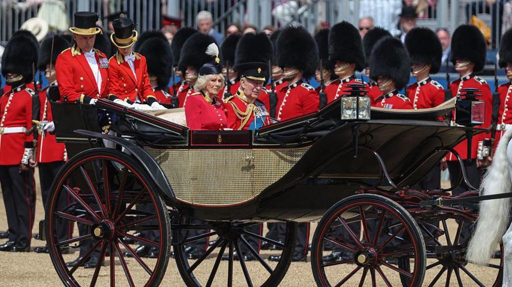 the king and queen in a horse drawn carriage.