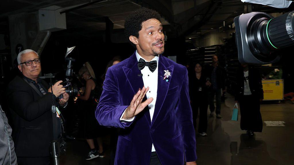 Trevor Noah wearing a purple suit at the Grammys. 