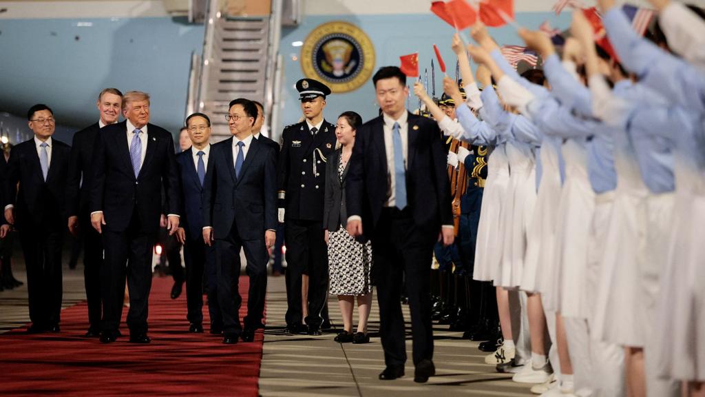 Donald Trump walks with Chinese Vice President Han Zheng and other delegates in front of Air Force One after arriving in Beijing, with people to the right waving Chinese and US flags