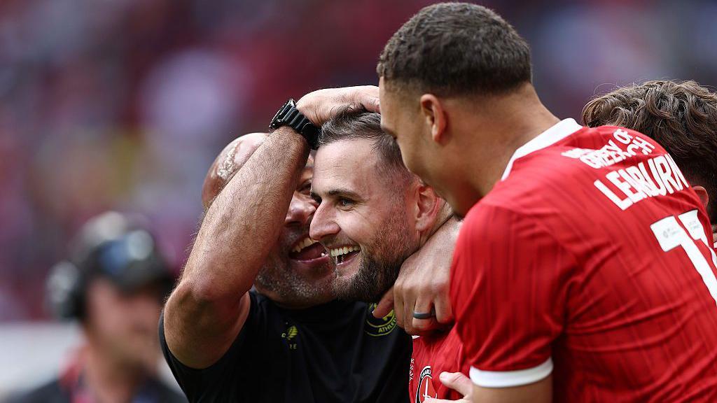 Macaulay Gillesphey (centre) is congratulated and hugged by Charlton Athletic players and coaching staff