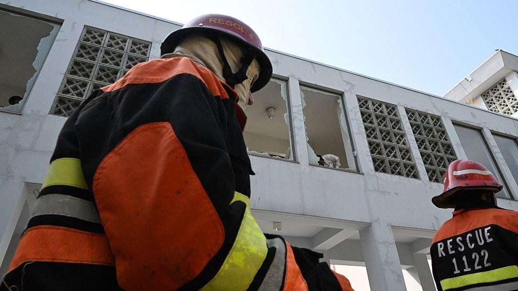 A firefighter walks past broken windows at the hospital