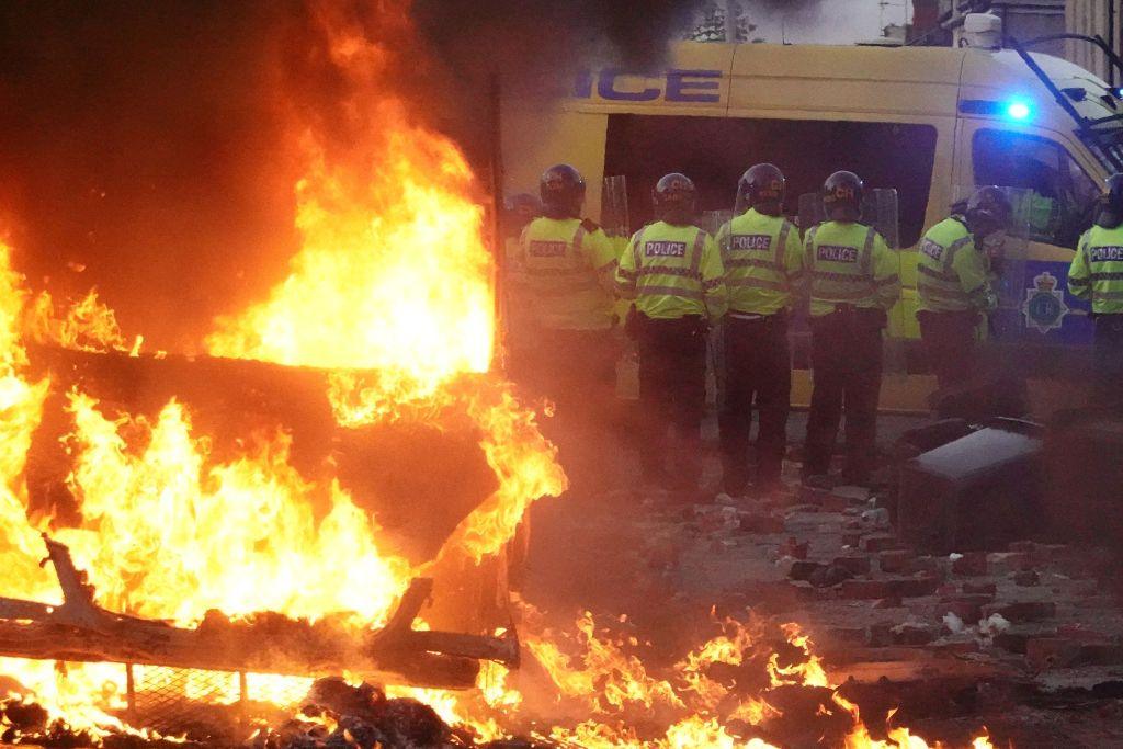  Riot police hold back protesters near a burning police vehicle after disorder broke out on in Southport