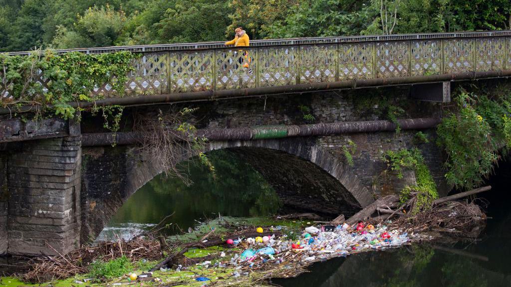 Sbwriel wedi casglu ger bont dros afon