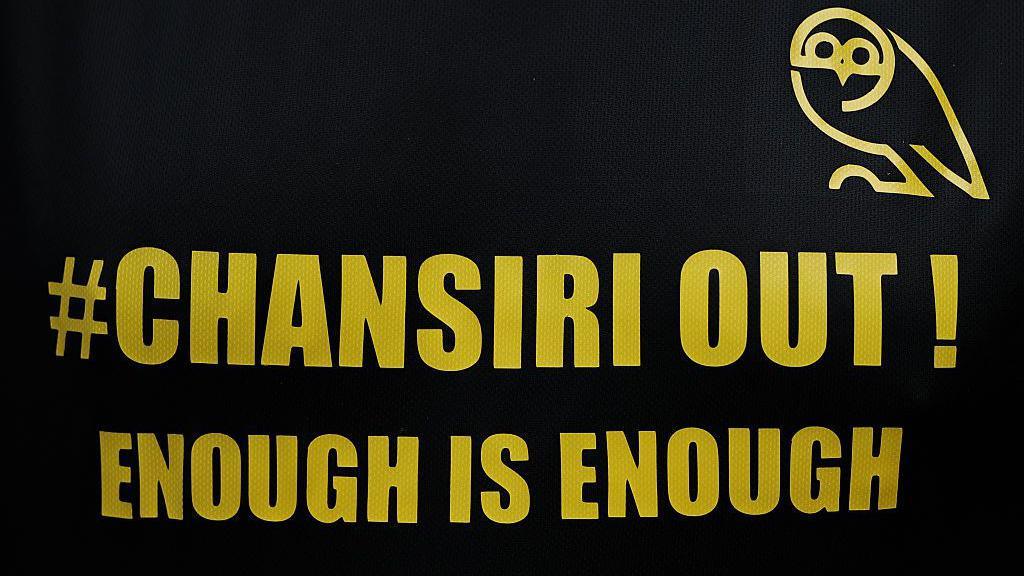 A black banner with yellow writing which says 'Chansiri out, enough is enough' is laid out by Sheffield Wednesday fans before their match against Stoke