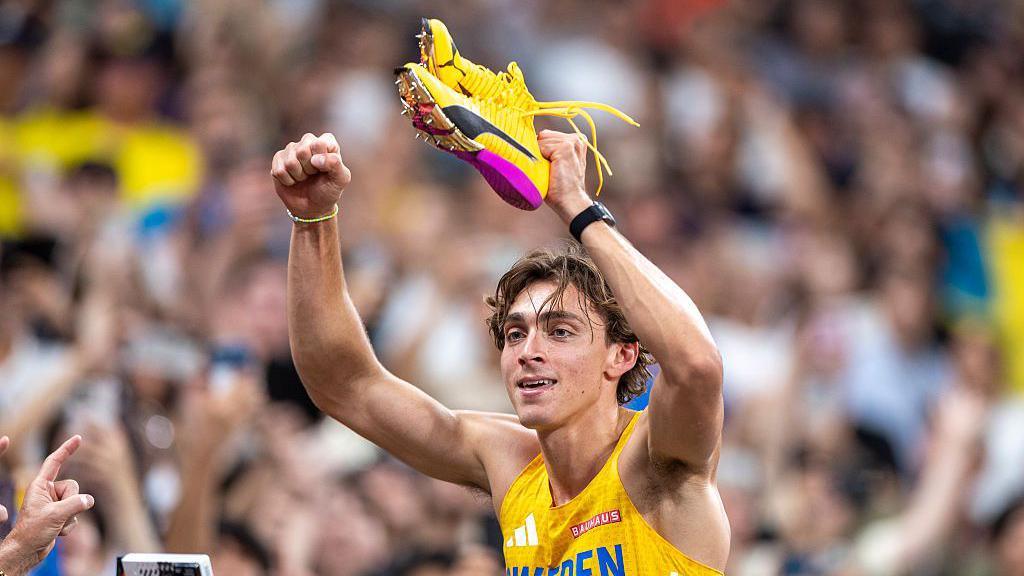 Armand Duplantis holds up his claw shoes