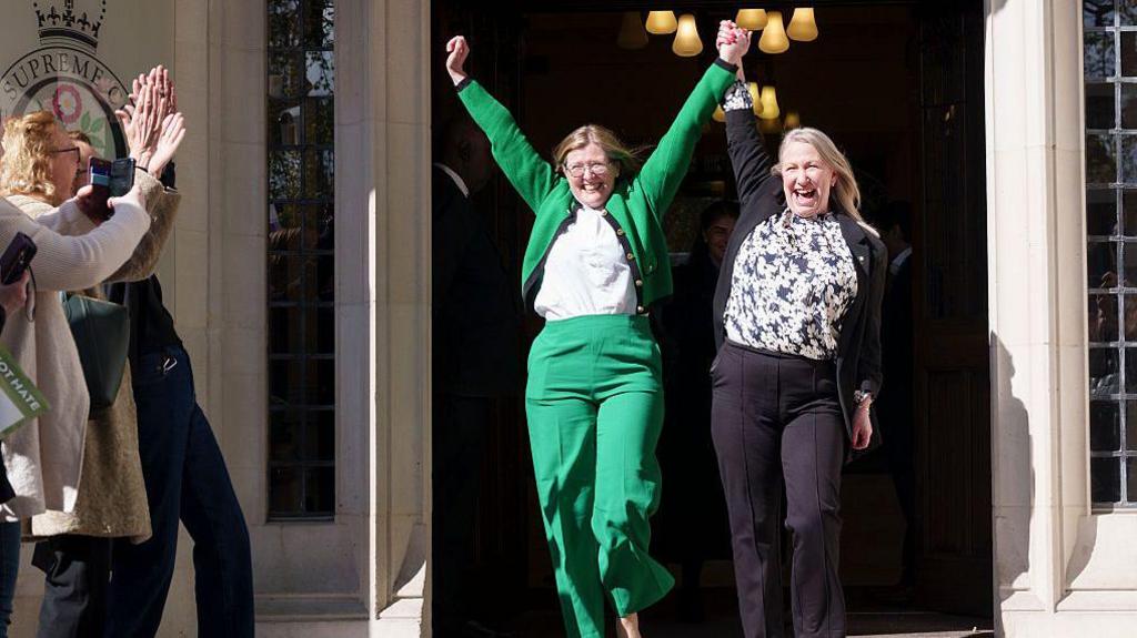 womens' rights campaigners Susan Smith (in green) and Marion Calder, both directors of 'For Women Scotland outside the Supreme Court in London. The women hold their hands above their heads in celebration at their victory