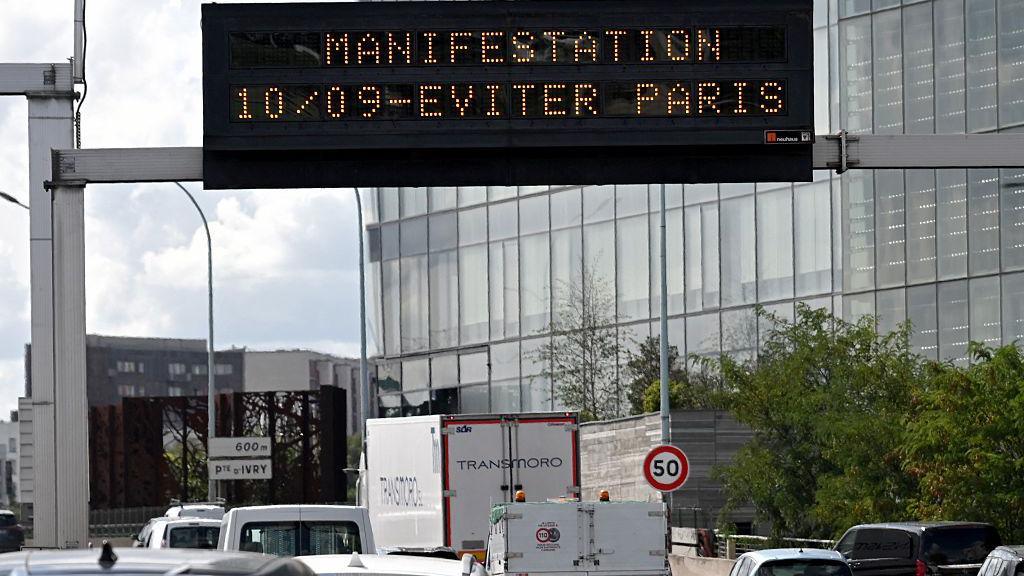A Paris billboard shows in orange - "demonstration 10/09 - avoid Paris"