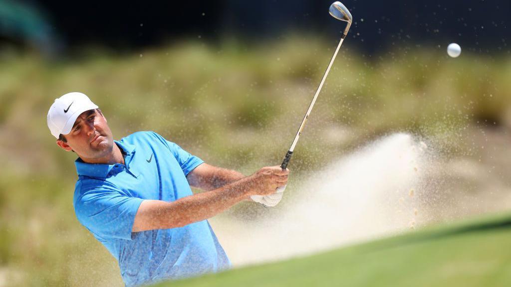 Scottie Scheffler hitting a ball out of a bunker during a practice round for the US Open at Pinehurst