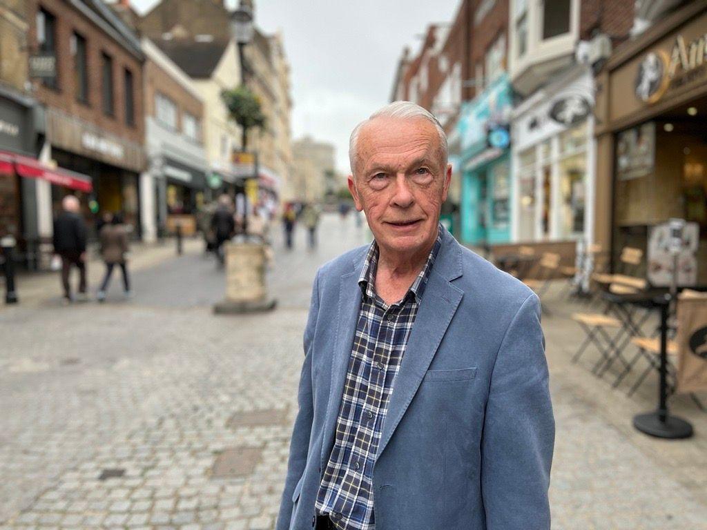 Robert Watson, a white man with white, short hair and a blue, checked shirt and a light blue blazer