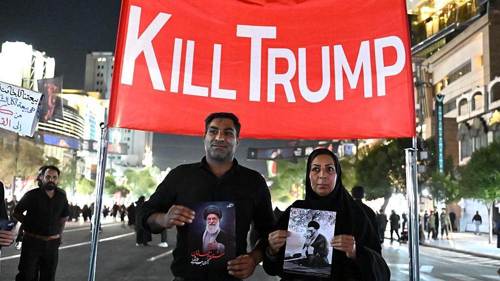 Mourners display an anti-US banner as they arrive near Imam Reza's shrine for the funeral of slain Iranian leader Ali Khamenei and members of his family in Mashhad early on July 9, 2026.