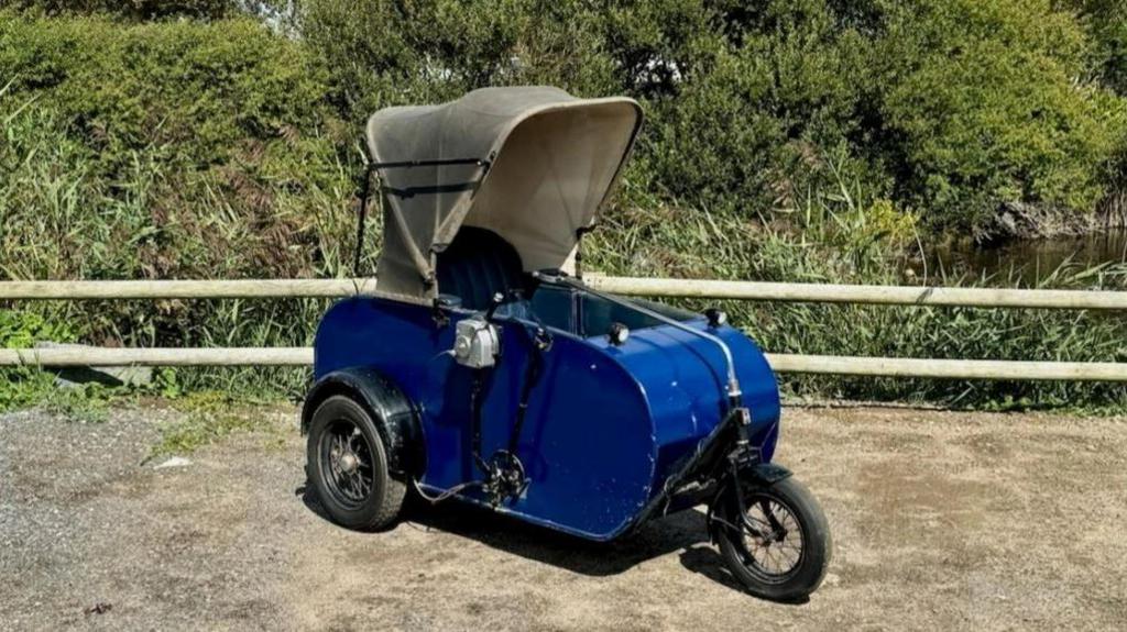 A colour picture of the carriage which looks like a motorcycle side-car. It is blue. 