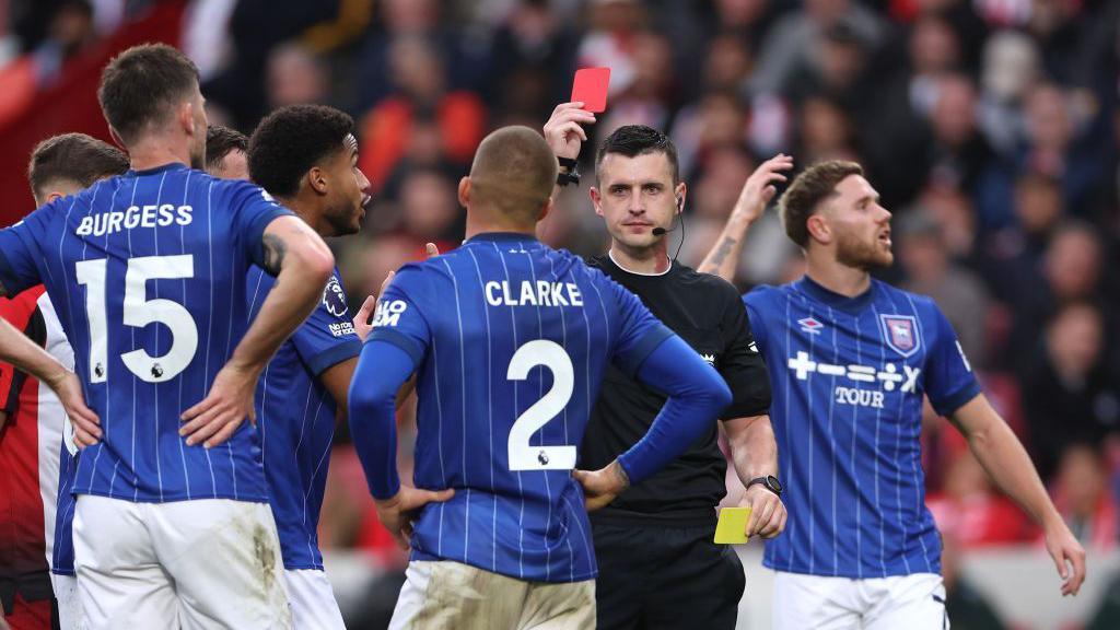 Harry Clarke of Ipswich Town is shown a red card by referee Lewis Smith after receiving a second yellow card for a foul on Keane Lewis-Potter of Brentford (not pictured) during the Premier League match between Brentford FC and Ipswich Town FC at Gtech Community Stadium