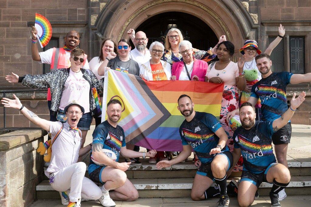 People posing with pride flag on steps