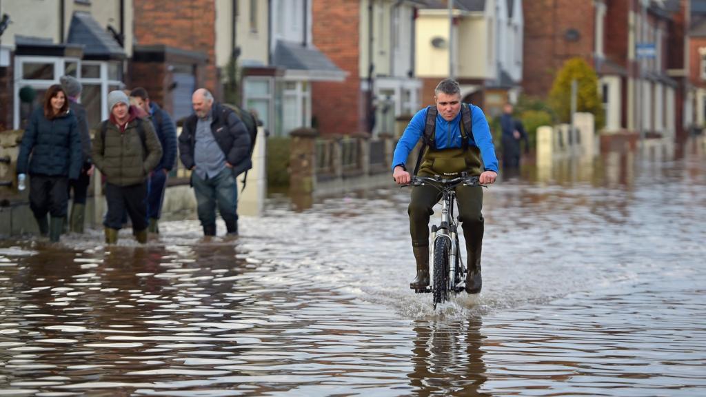 Man rides bike through floodwater