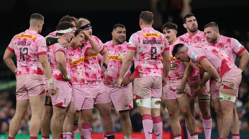 Harlequins players stand together on the pitch during their game against Bristol