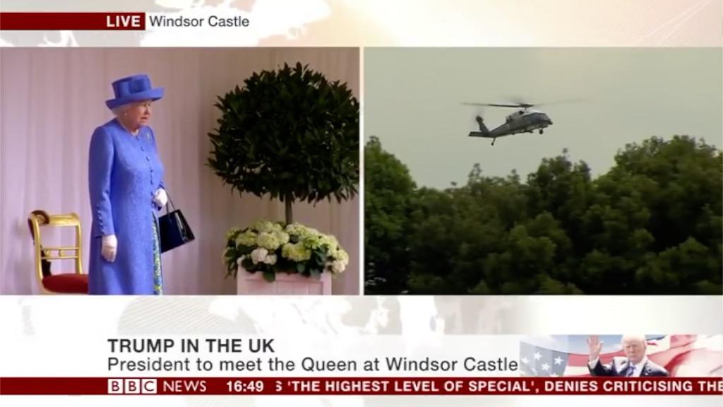 Screenshot of the Queen stood on the dais outside Windsor Castle and on a split screen President Trump's helicopter