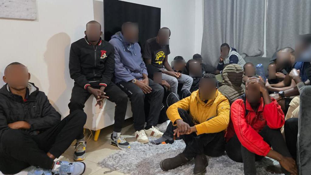 Men sitting on coaches and others on carpet with their eyes blurred 
