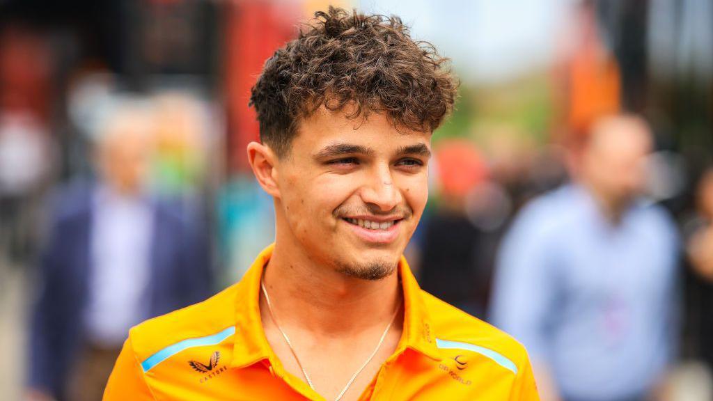 Lando Norris smiles as he arrives in the paddock at Imola 