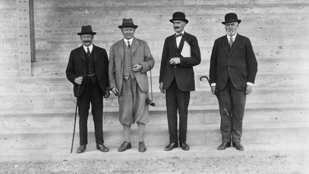 A black and white image of four men who are all smartly dressed in suits and hats