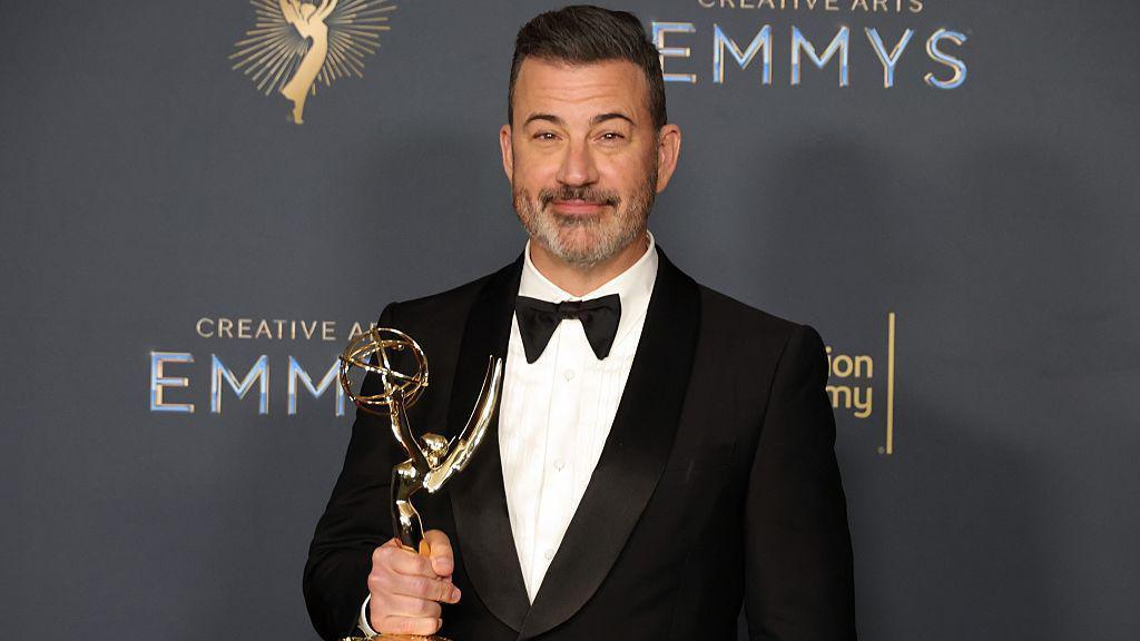 Jimmy Kimmel in a tuxedo holding an Emmy award.