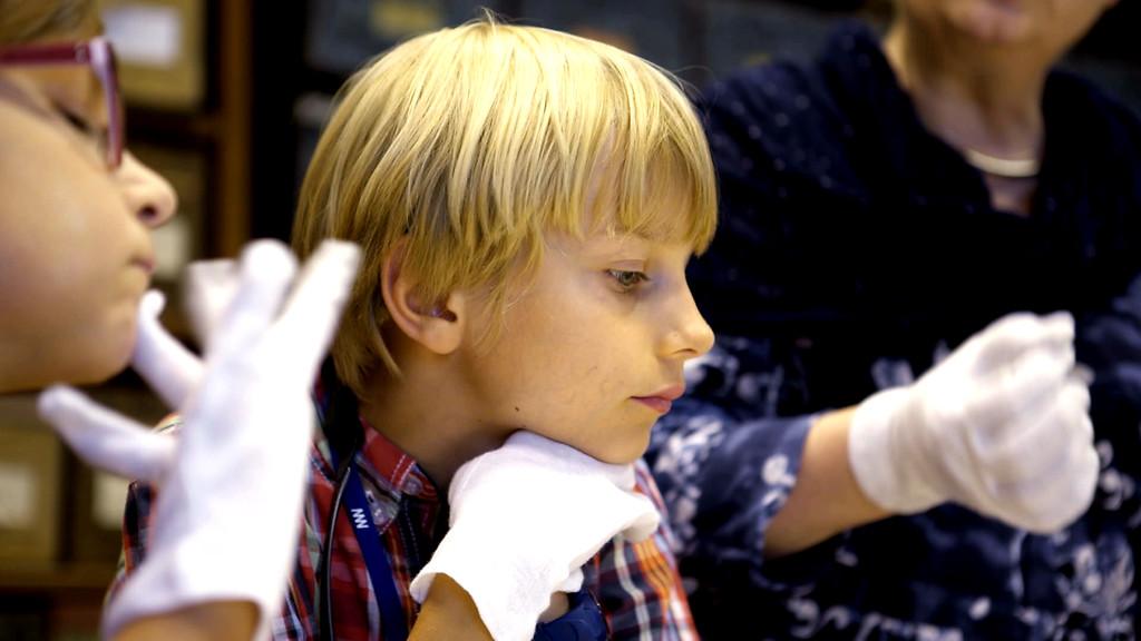 Children in white gloves working on the exhibition