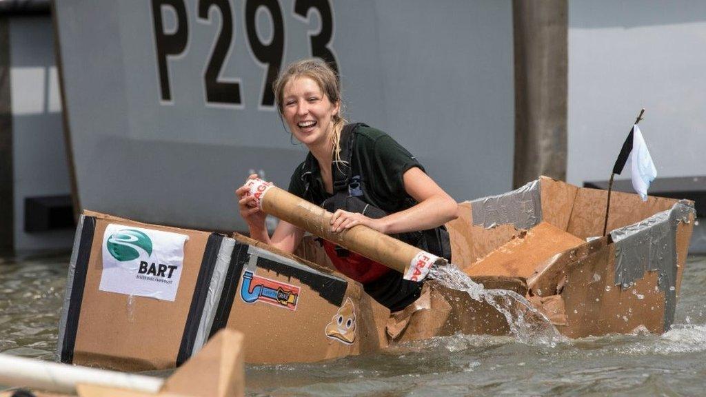 A woman racing in last year's competition- she is directing a carboard boat in the harbour