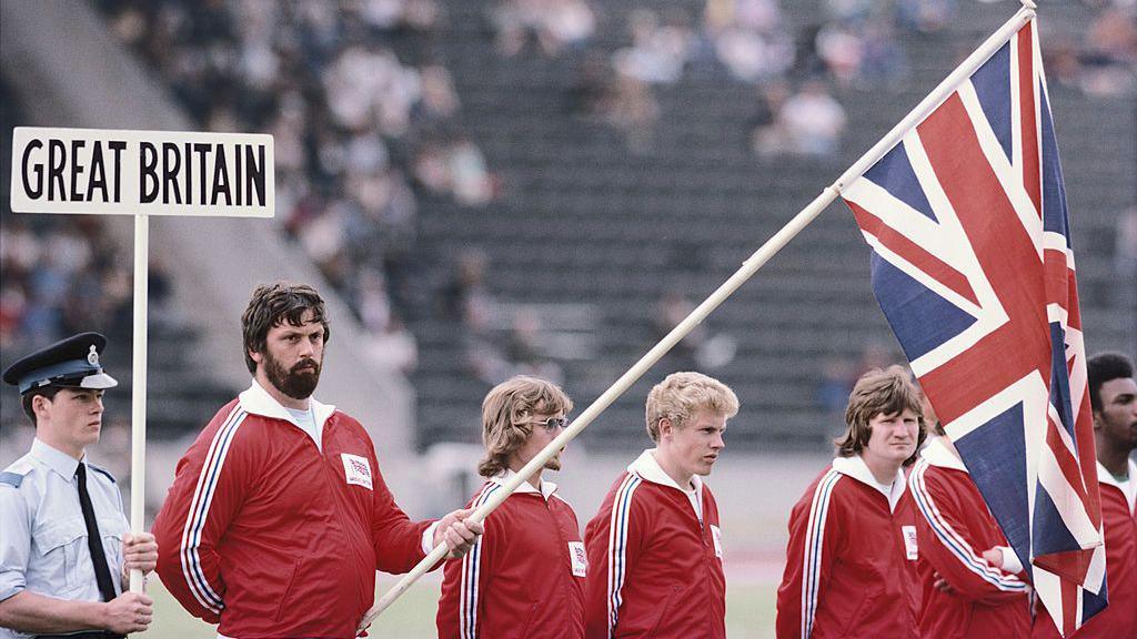 Geoff Capes holds a Union Jack flag while standing with Great Britain team-mates