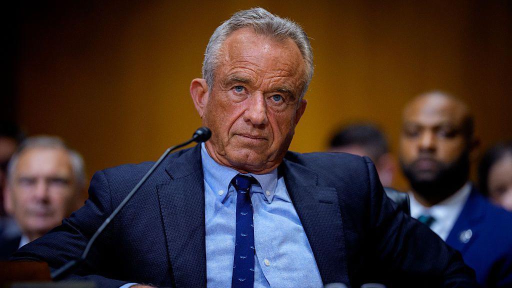 US Health Secretary Robert F Kennedy seated in front of a microphone in the US Senate, wearing a blue suit.