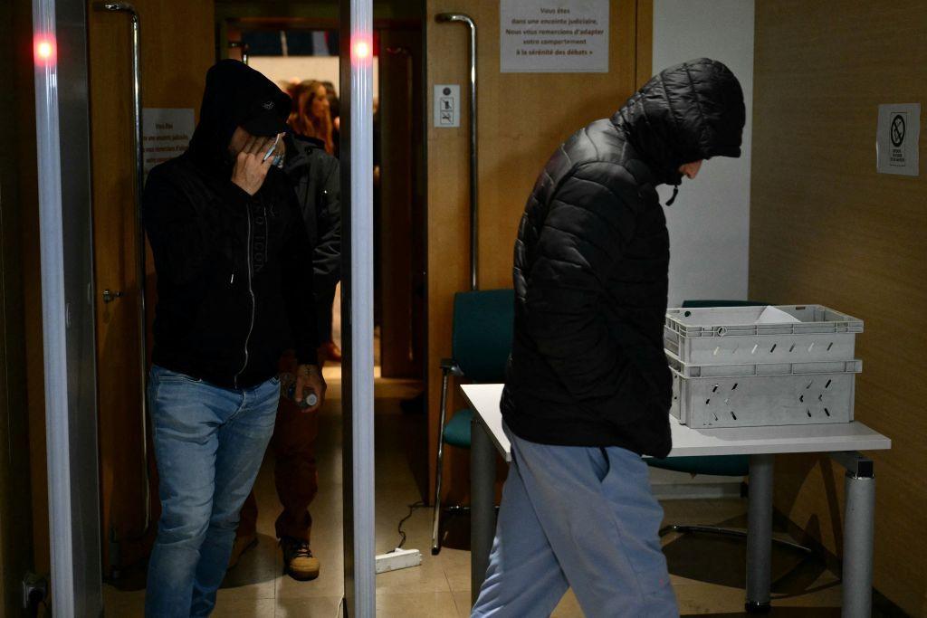 Two men wearing their hoods up leave the courtroom