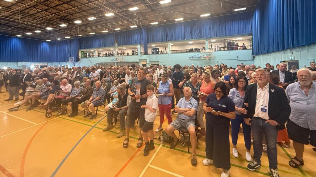 A crowd of people in a sports hall.