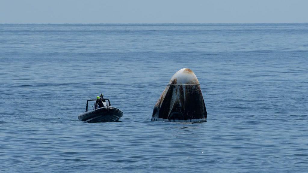 A recovery support team flanks the SpaceX's Crew Dragon capsule spacecraft