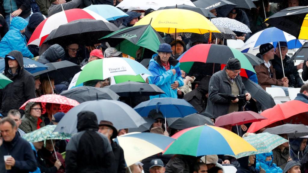 Fans shelter under their umbrellas