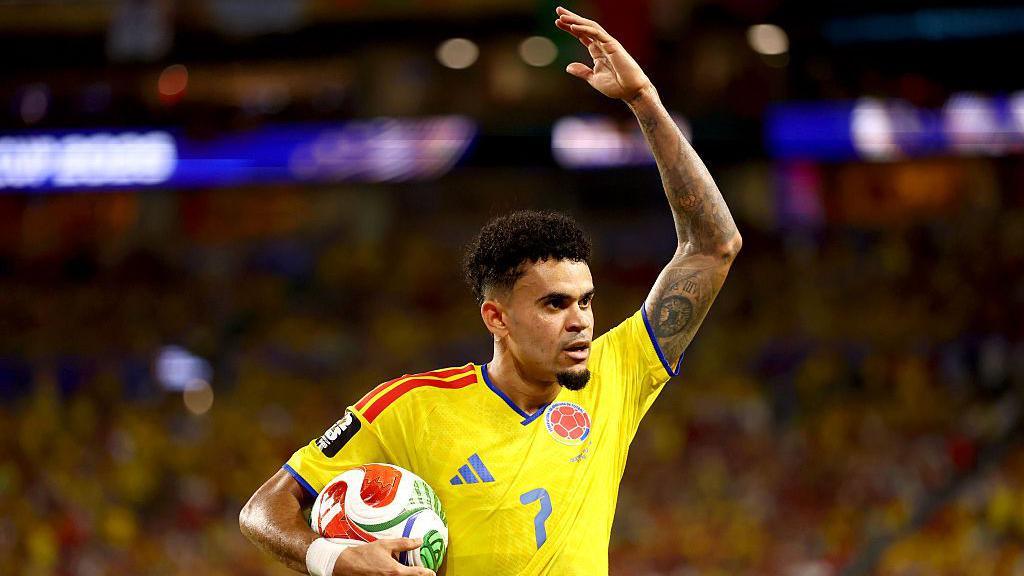 Luis Diaz celebrates with the crowd while holding the ball