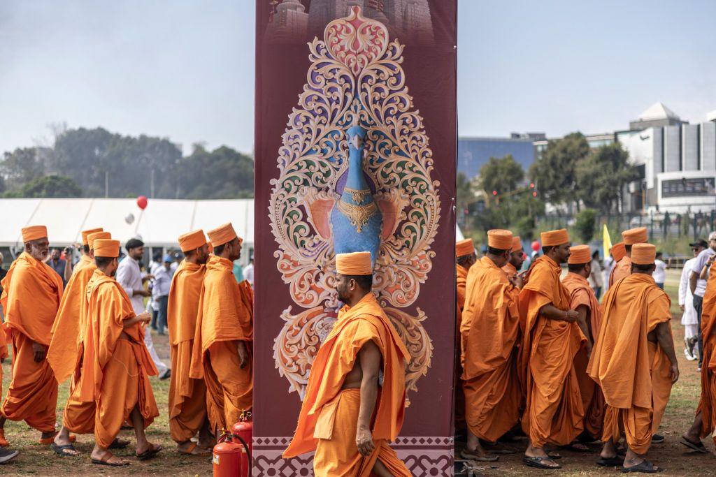 Men gather wearing the same orange gowns and matching head covering.