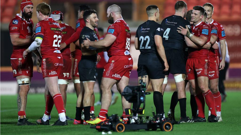 Scarlets and Ospreys players greet each other after their game