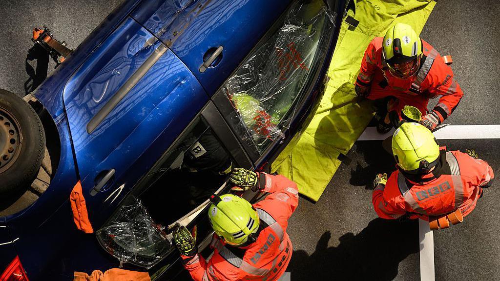 LFB demonstrate how to extract an injured person from a car. The car has broken windows and is on its side