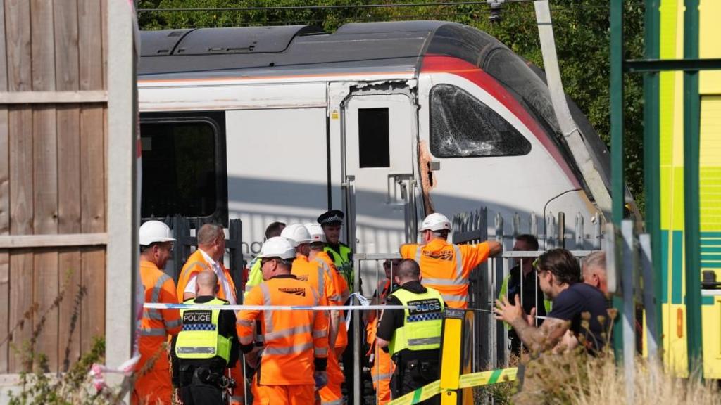 Rail workers and police officers investigate at the scene where a Greater Anglia train derailed.