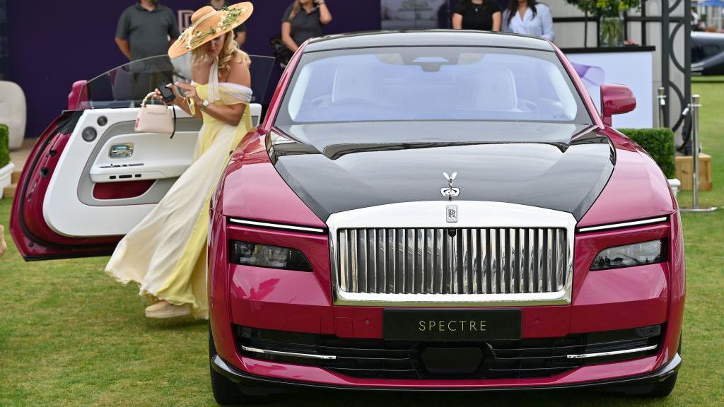 Rolls Royce spectre with woman dressed in straw hat an flowing yellow dress