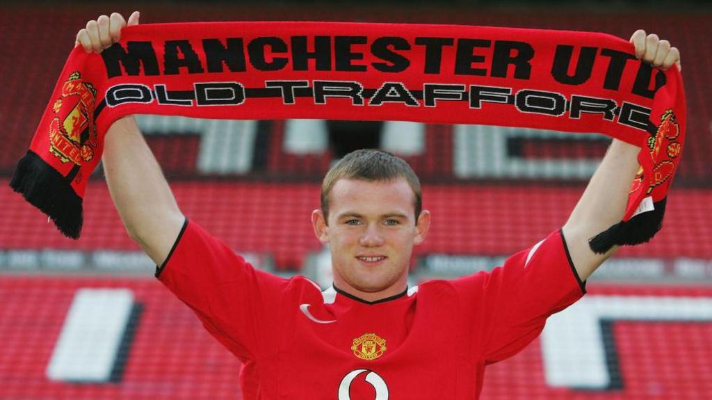 Wayne Rooney holds up a Manchester United scarf after joining the club