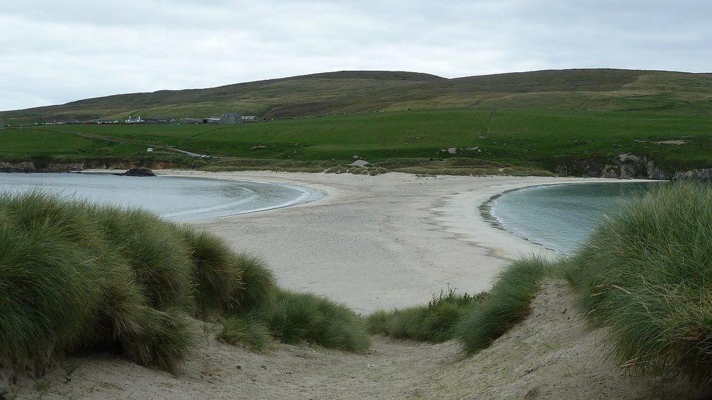 a beach which has water on either side and hills in the background